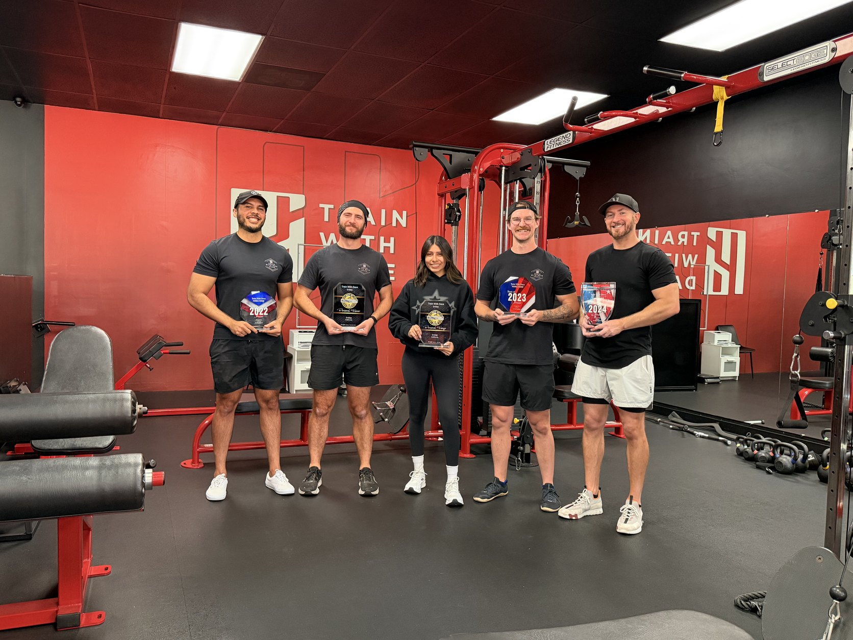 The Train With Dave Irvine coaching team holding their award plaques inside the Irvine studio